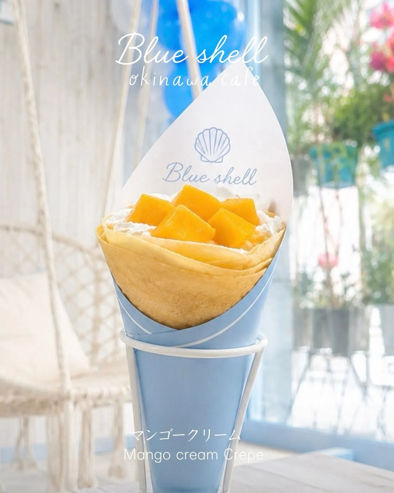 スタンドに立てられたマンゴークレープ。「Blue shell okinawa cafe」「マンゴークリーム Mango cream Crepe」の文字。