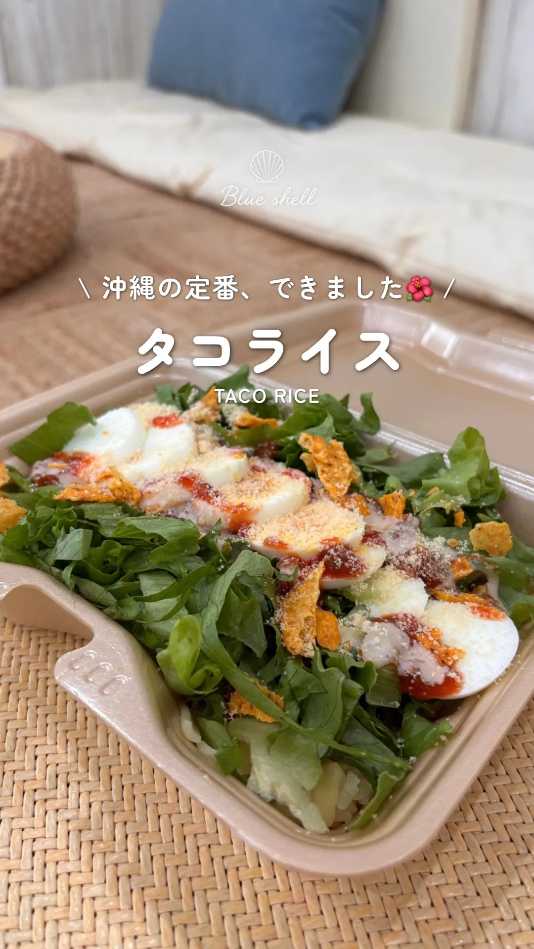 テイクアウト容器に入ったタコライス。「Blue shell」「＼沖縄の定番、できました🌺／」「タコライス TACO RICE」の文字。
